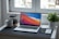 A clean and modern workspace with a laptop and a cup of coffee on a wooden desk.