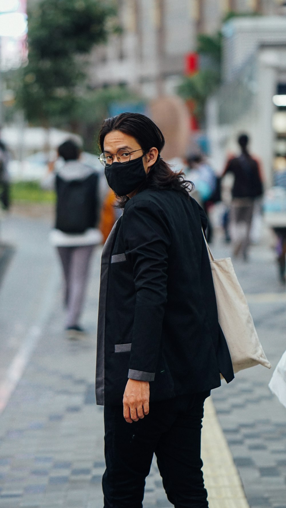 woman in black coat and black sunglasses standing on road during daytime