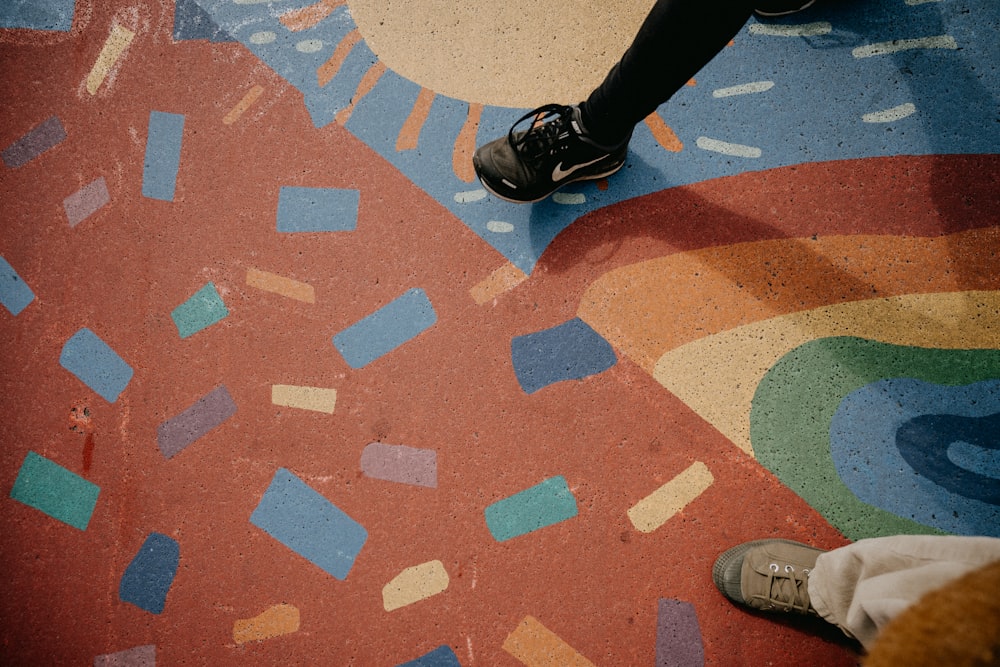 person in black pants and black shoes standing on brown and white concrete floor