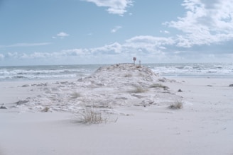 person standing on white sand near sea under blue sky during daytime