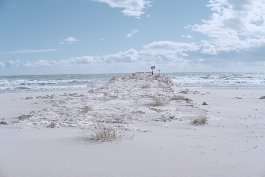 person standing on white sand near sea under blue sky during daytime