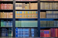 A vibrant display of books arranged by color on a wooden shelf.