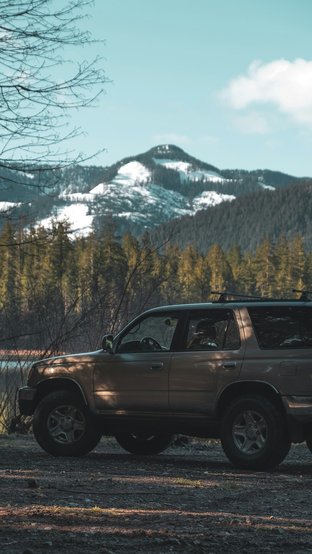 black suv on road near green trees and snow covered mountain during daytime