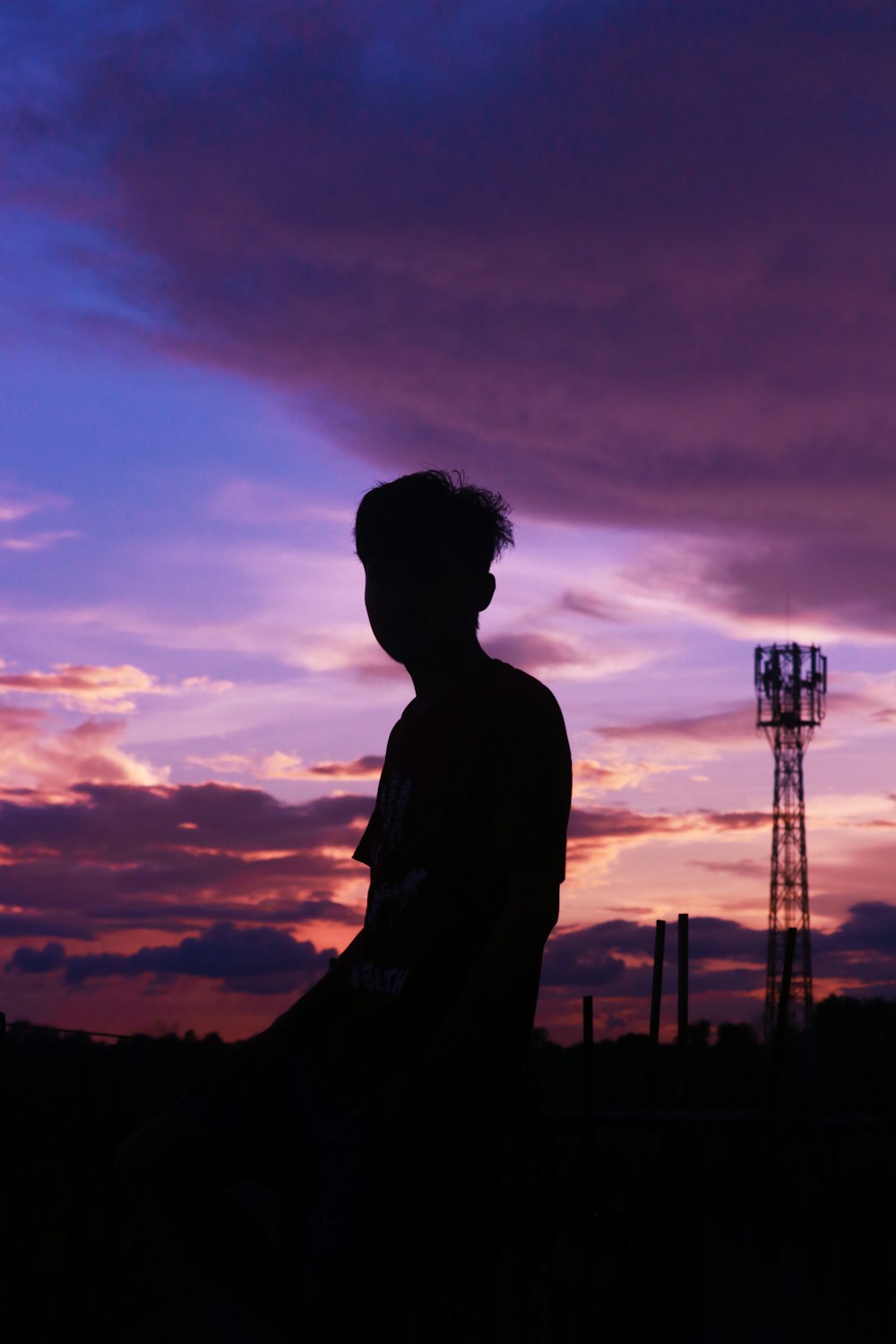 silhouette of man standing near tower during sunset