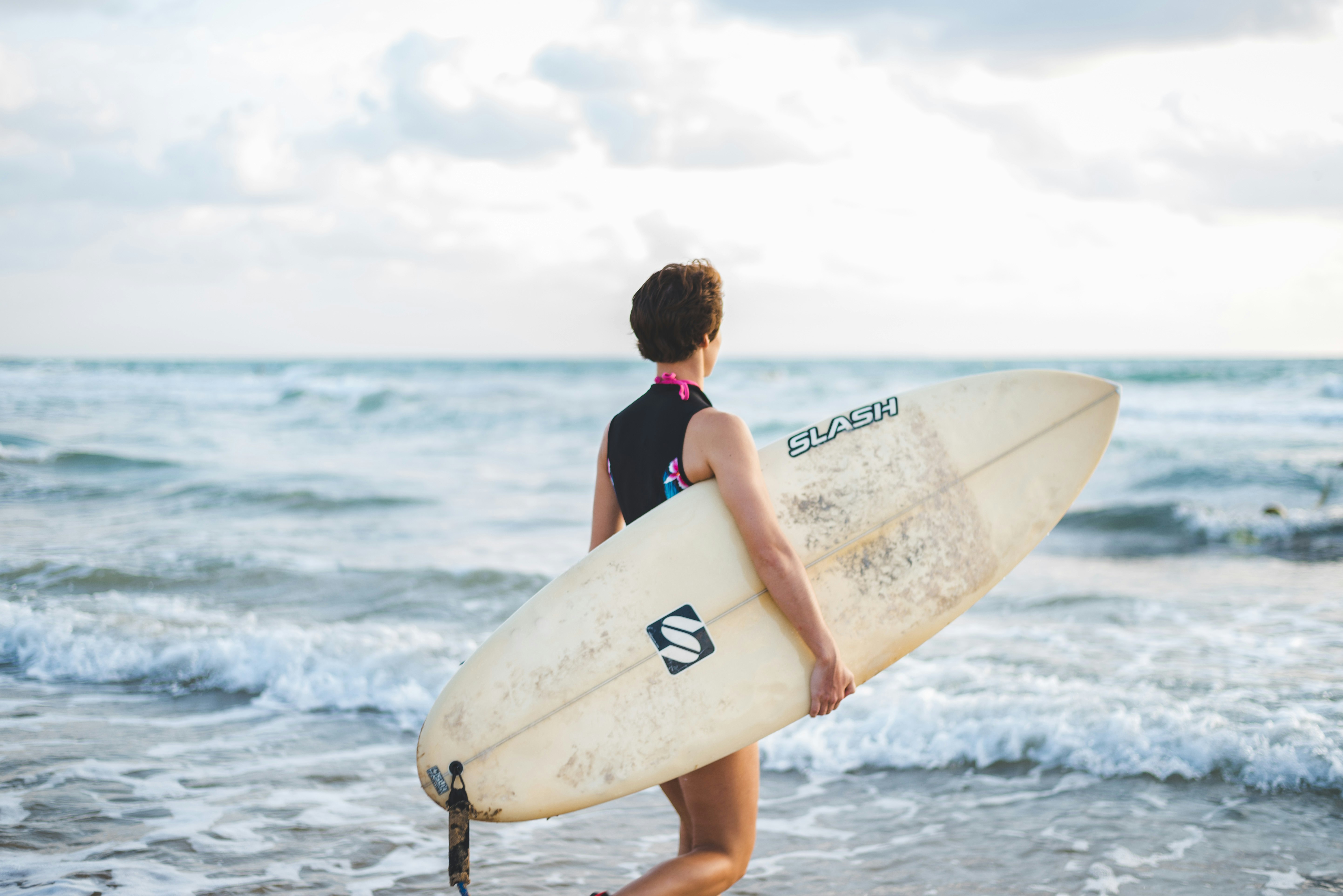 woman in blue and black bikini holding white surfboard