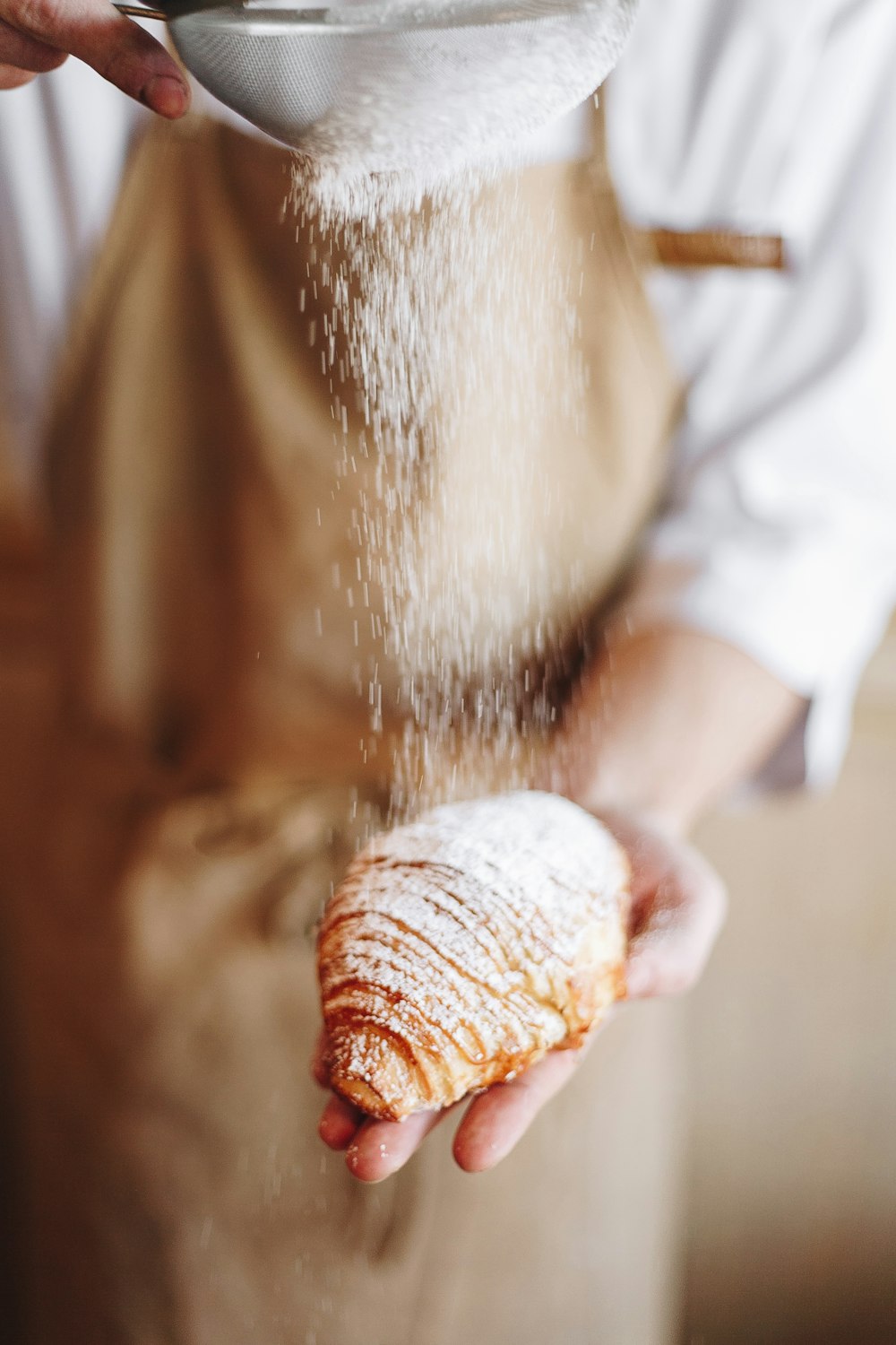 person in white shirt holding brown bread