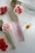 Three perfume bottles with elegant gold caps are arranged alongside vibrant red and white flowers on a sleek, white surface.