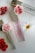 Three perfume bottles with elegant gold caps are arranged alongside vibrant red and white flowers on a sleek, white surface.