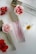 Three perfume bottles with elegant gold caps are arranged alongside vibrant red and white flowers on a sleek, white surface.