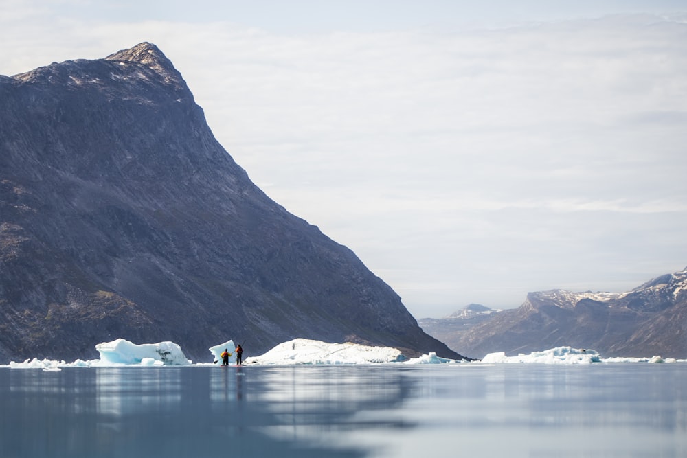 white boat on water near mountain during daytime