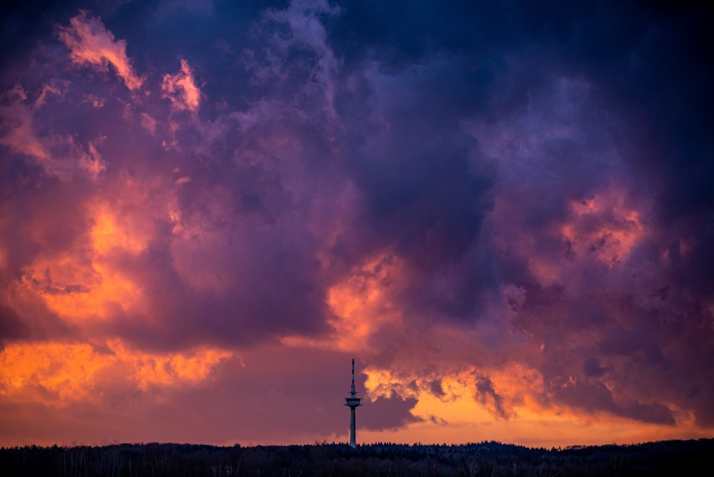 silhouette of windmill under cloudy sky during sunset