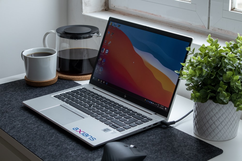 macbook pro beside white ceramic mug on black table