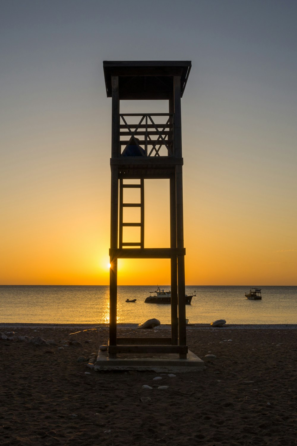 日没時のビーチにある茶色の木製のライフガードタワー