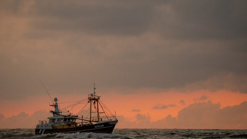 white and black boat on sea during sunset