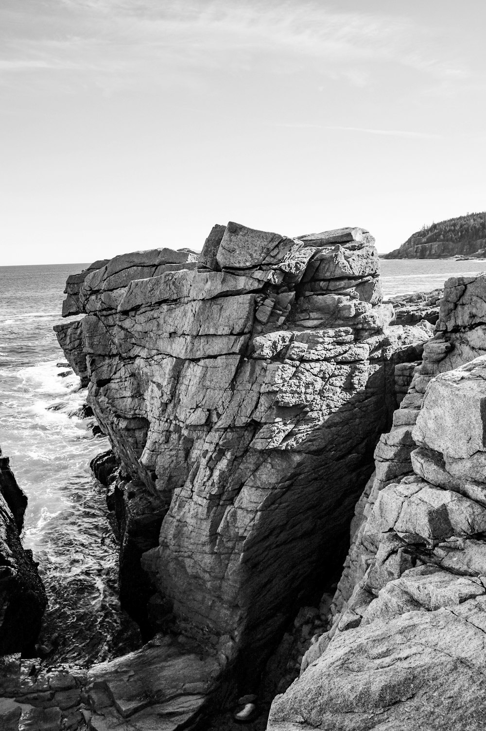 grayscale photo of rocky mountain by the sea