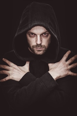 man in black hoodie covering his face with his hand