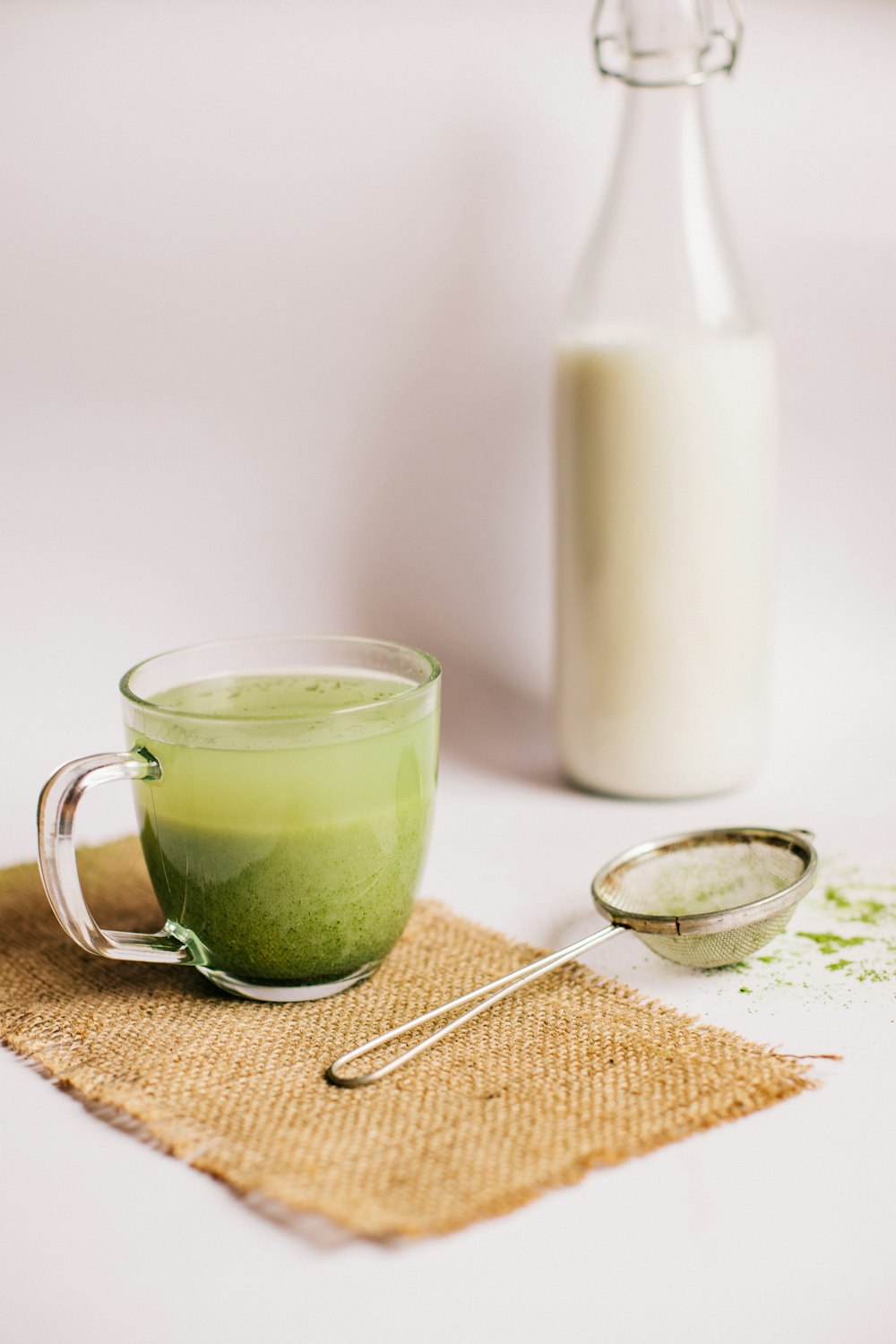 green liquid in clear glass mug beside white pillar candle