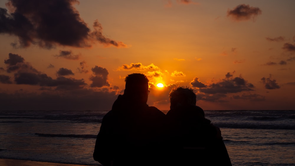 silhouette of couple sitting on bench during sunset