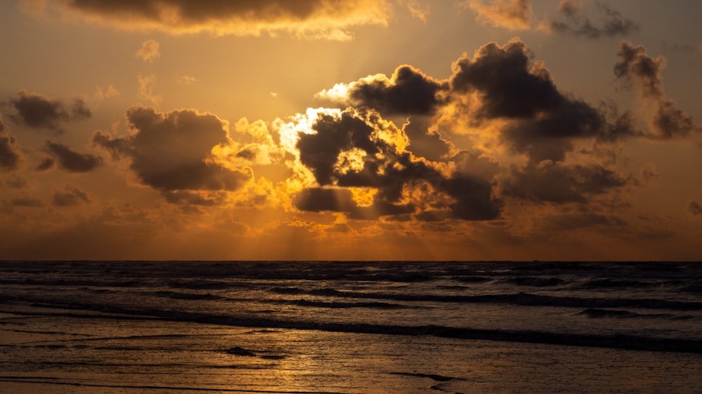 body of water under cloudy sky during sunset