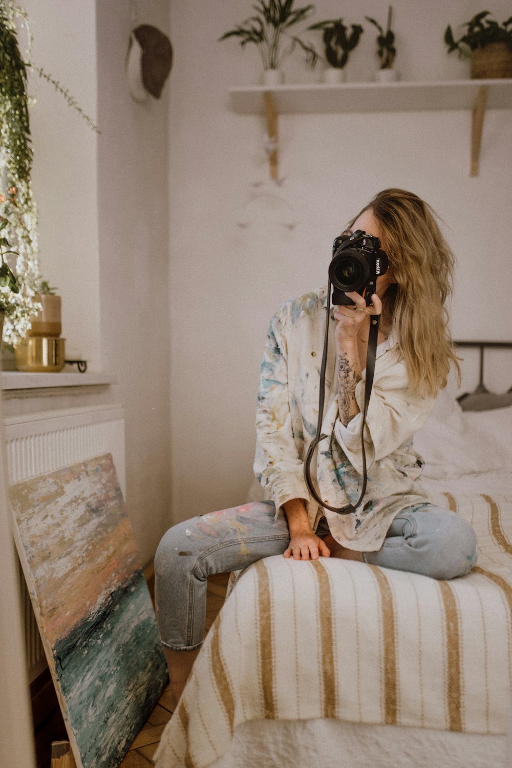 woman in white long sleeve shirt and blue denim jeans sitting on white and brown stripe