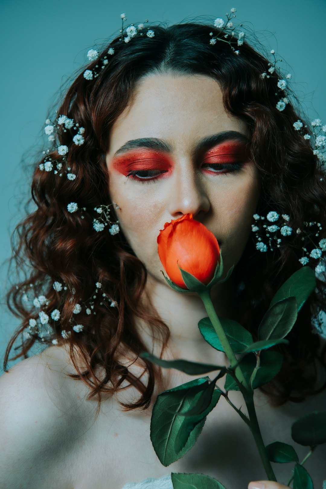 woman with red lipstick and white flower on her ear