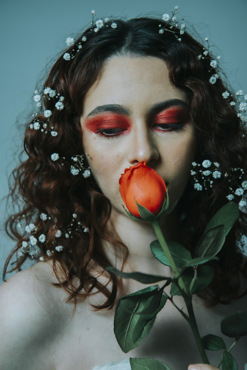 woman with red lipstick and white flower on her ear