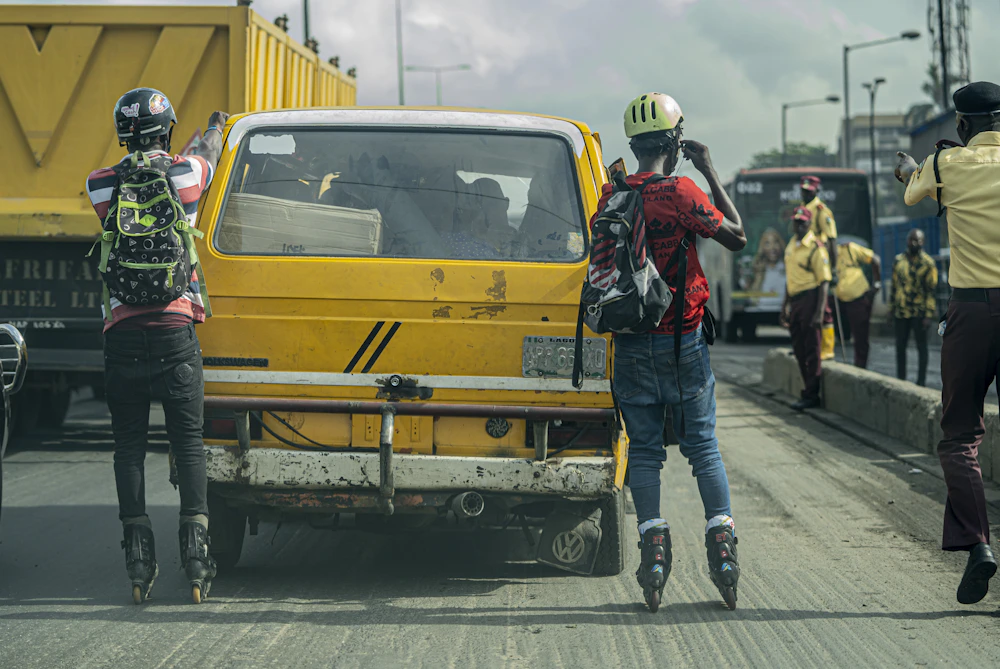 Rollerbladers holding onto a yellow danfo bus on a busy Lagos street