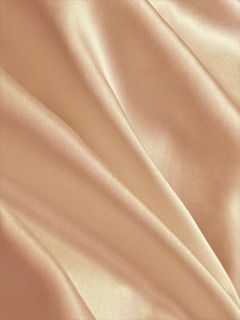 Smooth, silky fabric with soft, flowing folds and a warm, beige color.