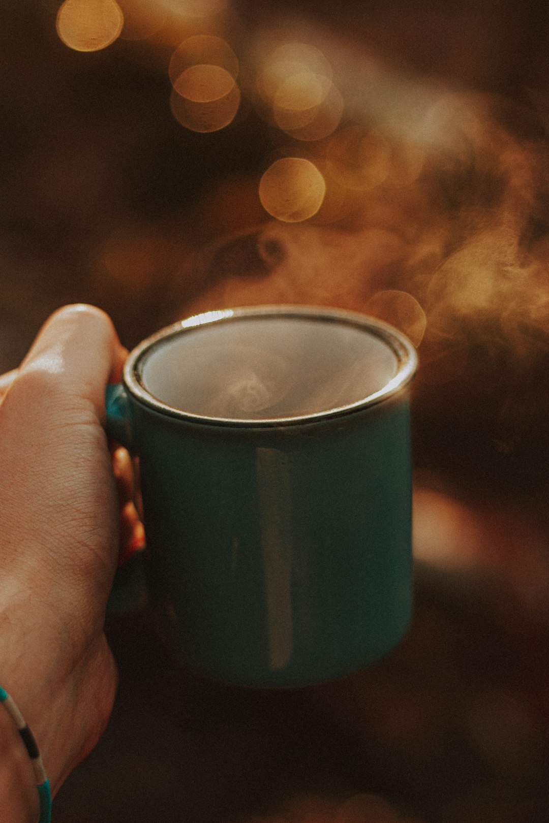 person holding blue ceramic mug with coffee