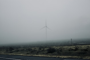 white wind mill on green grass field under white sky during daytime