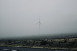 white wind mill on green grass field under white sky during daytime