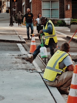man in yellow and black safety vest holding blue plastic bucket