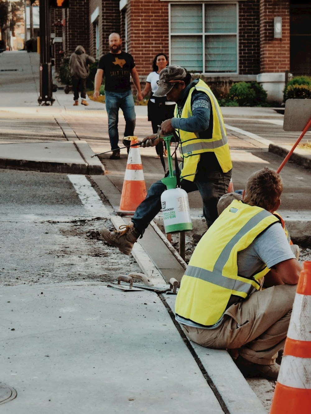 man in yellow and black safety vest holding blue plastic bucket