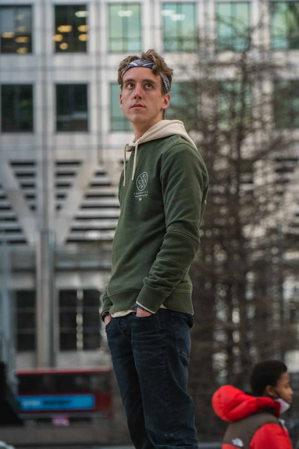 man in green long sleeve shirt and blue denim jeans standing on snow covered ground during