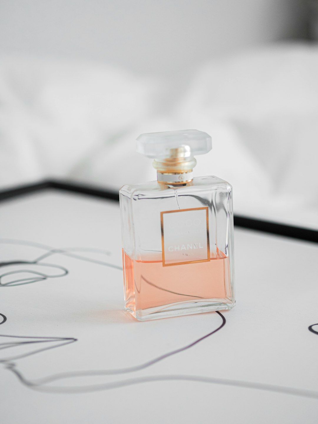 clear glass perfume bottle on white surface