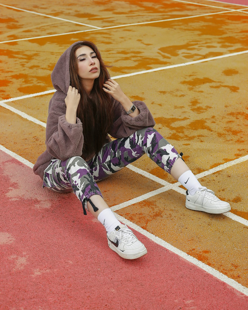 woman in gray sweater and black and white pants sitting on red and white concrete floor