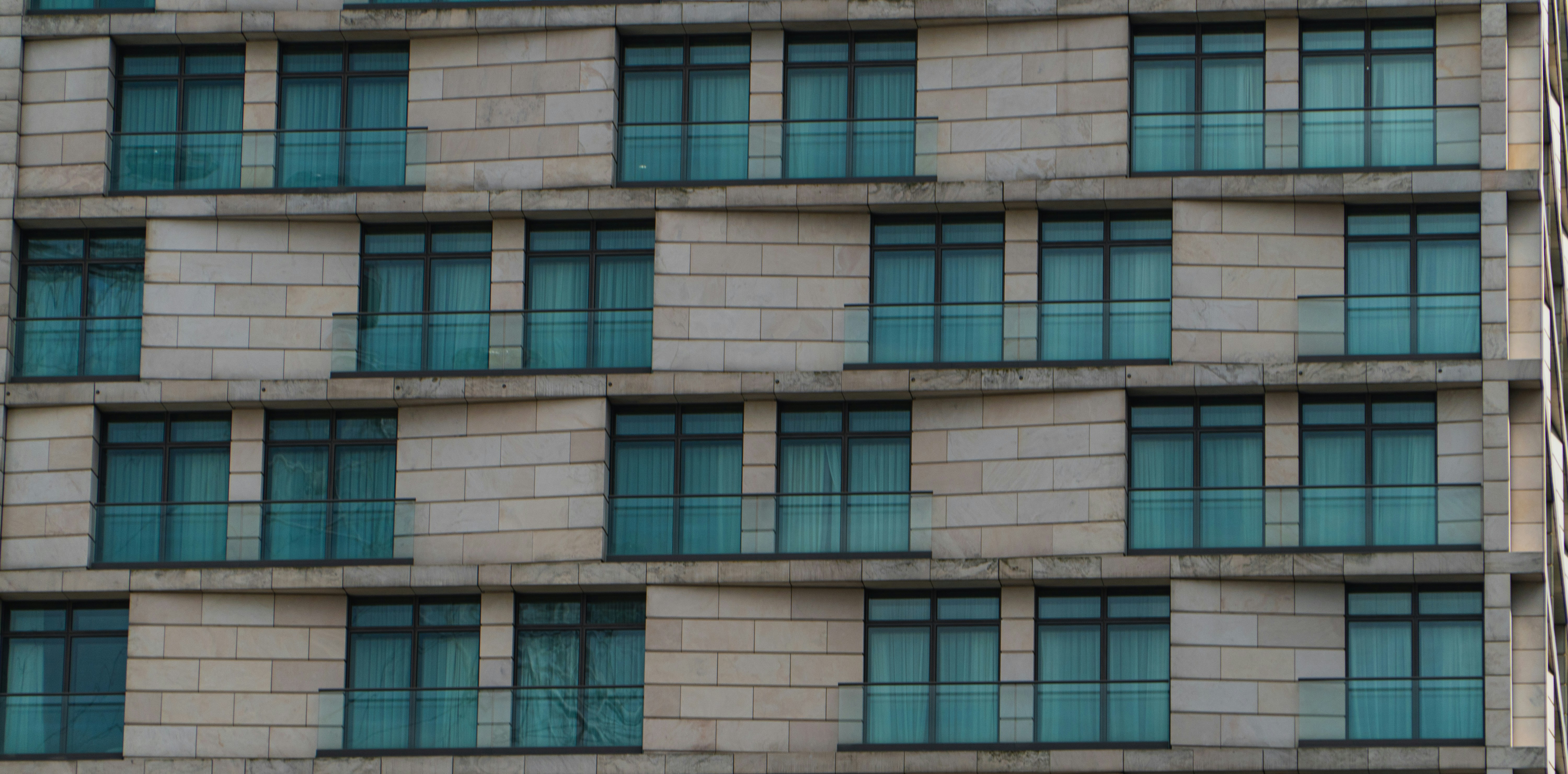 A professional realtor or contractor stands in front of a modern building, using a tablet to track business results and client data on-site.