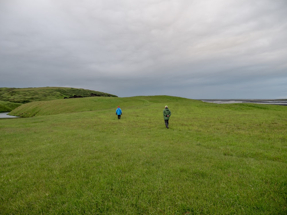 2 person walking on green grass field during daytime