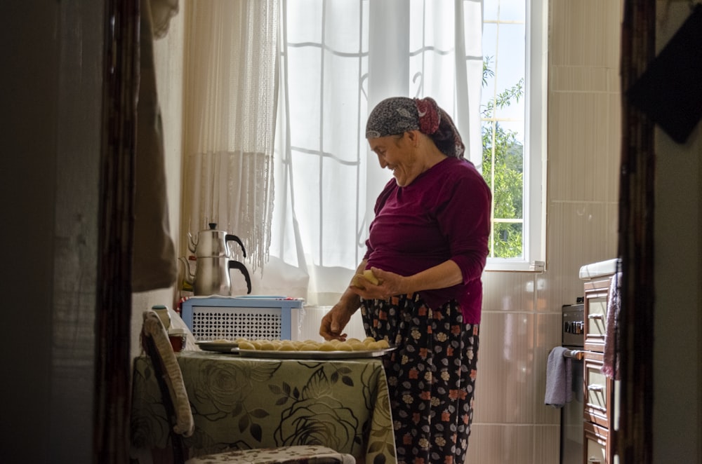 woman in purple shirt standing near window