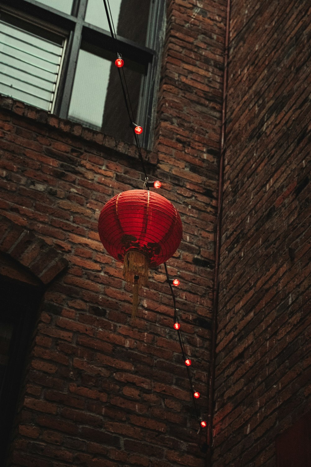 red paper lantern hanging on brown brick wall