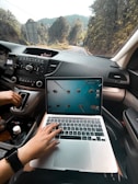 person using macbook air on car