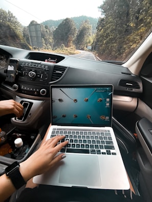 person using macbook air on car