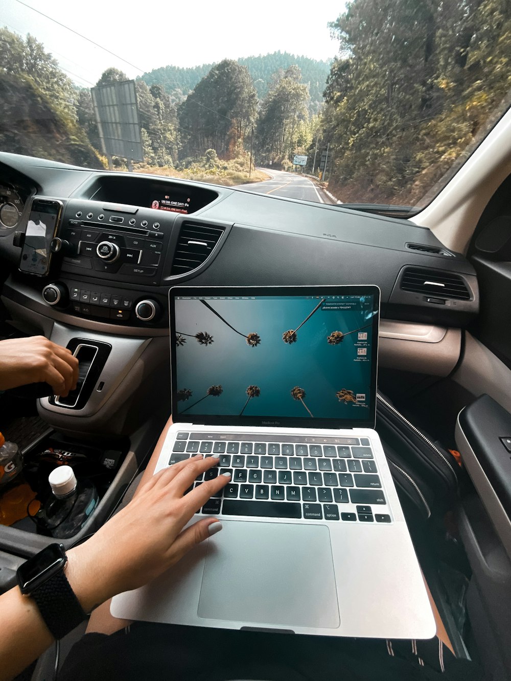 person using macbook air on car