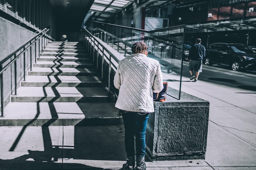 man in white dress shirt and blue denim jeans standing on stairs