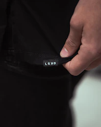 Close-up of hands carefully inspecting a high-quality custom logo on a black t-shirt.