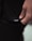 A close-up image of a person's hand holding the hem of a black garment with a small white label displaying the letters 'LSKD'. The lighting is soft, creating subtle shadows and highlights on the fabric and skin.