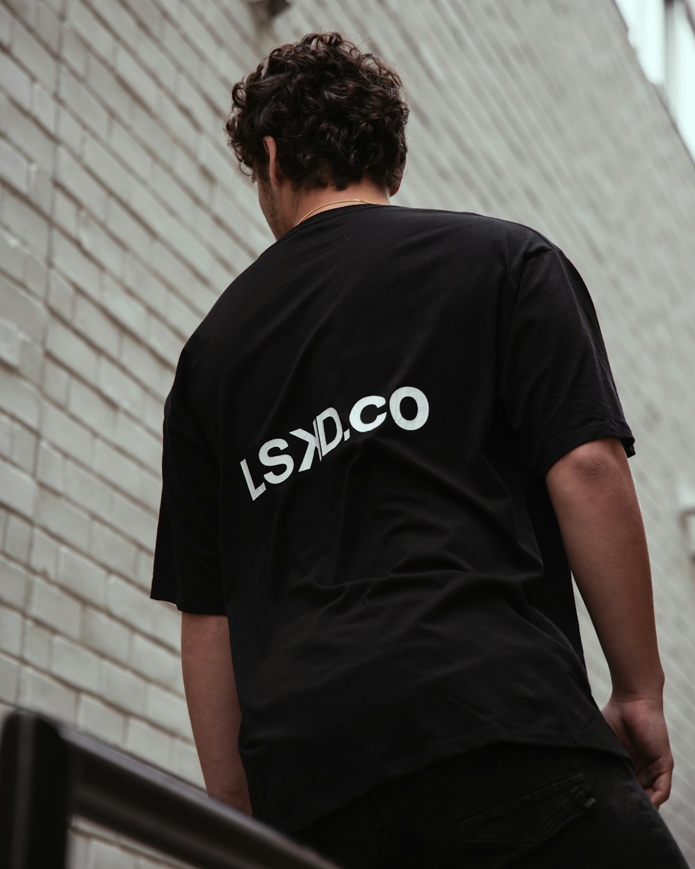 man in black t-shirt standing near white wall