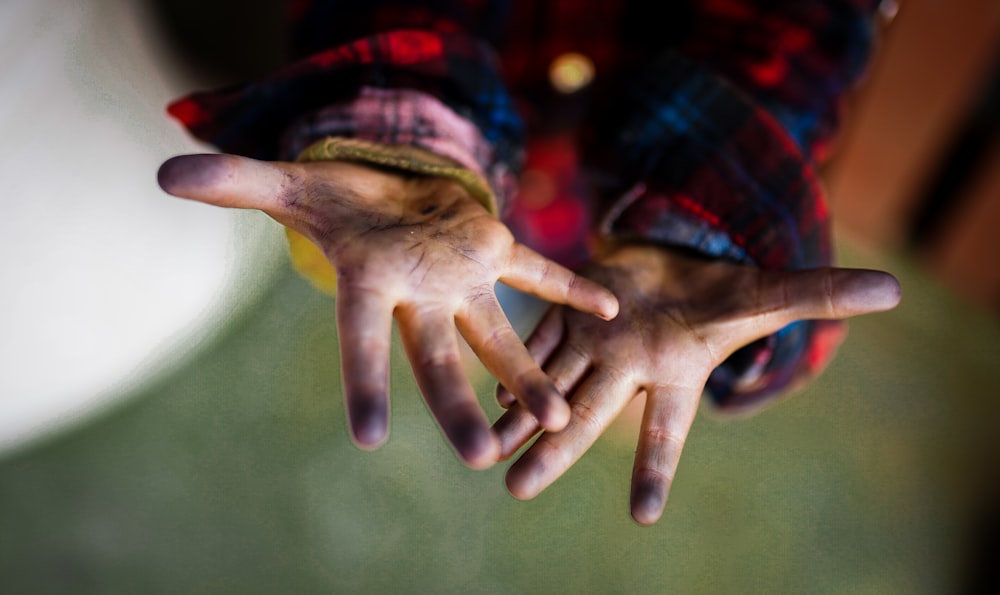 person in blue red and black long sleeve shirt covering face with hand