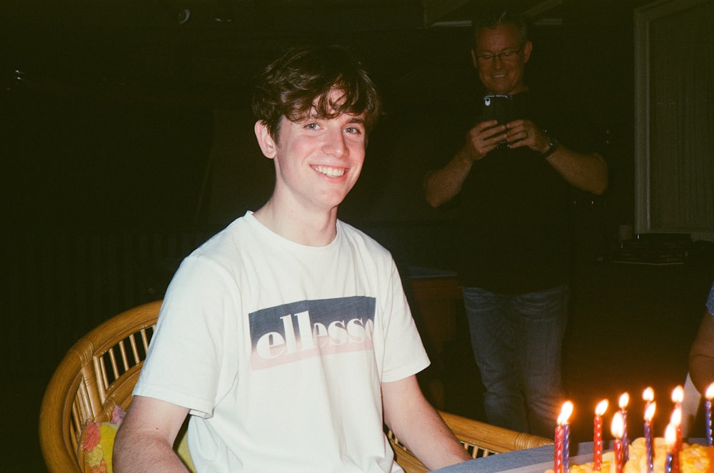 man in white crew neck t-shirt holding lighted candle