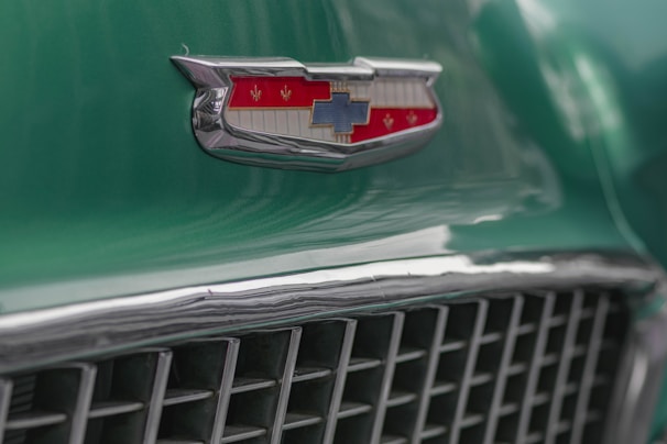 An artistic shot of a shiny chrome car emblem reflecting the vibrant colors of the American flag-themed decorations at the show.